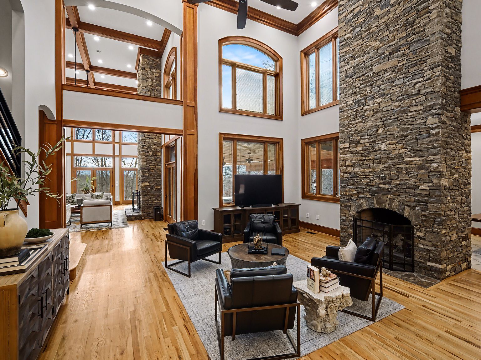 The two-story great room with stacked-stone fireplace, exposed beams, and oak floors