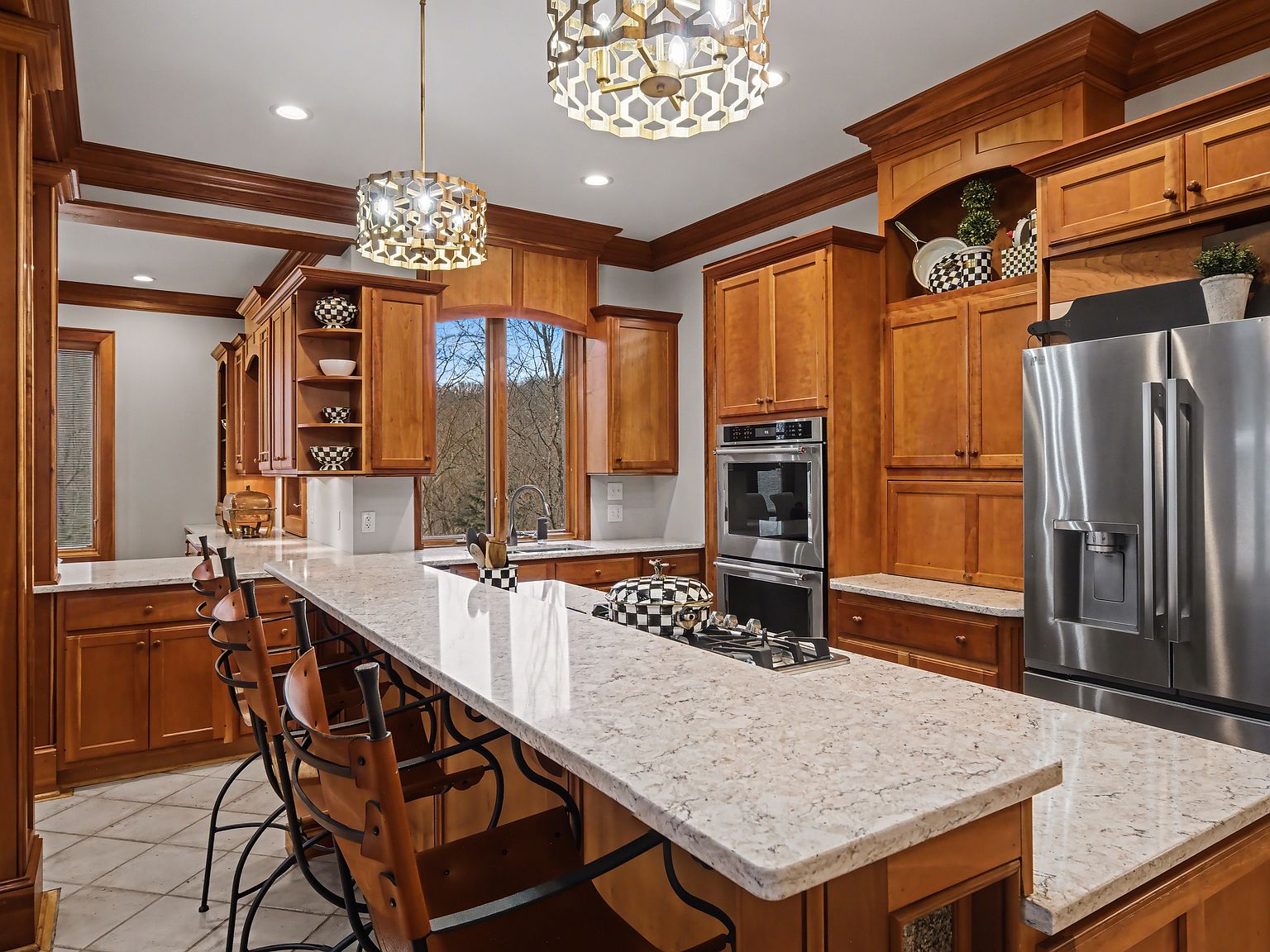 A second view of the kitchen showing the granite island, custom cabinetry, and arched window over the sink