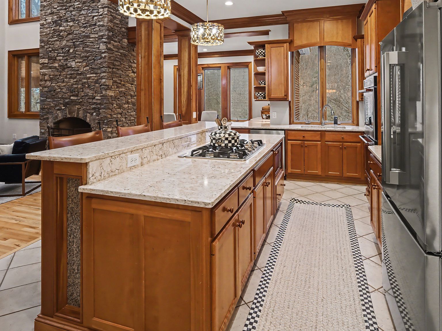 The kitchen seen past a stacked-stone column, with the wooded ridge visible through the window