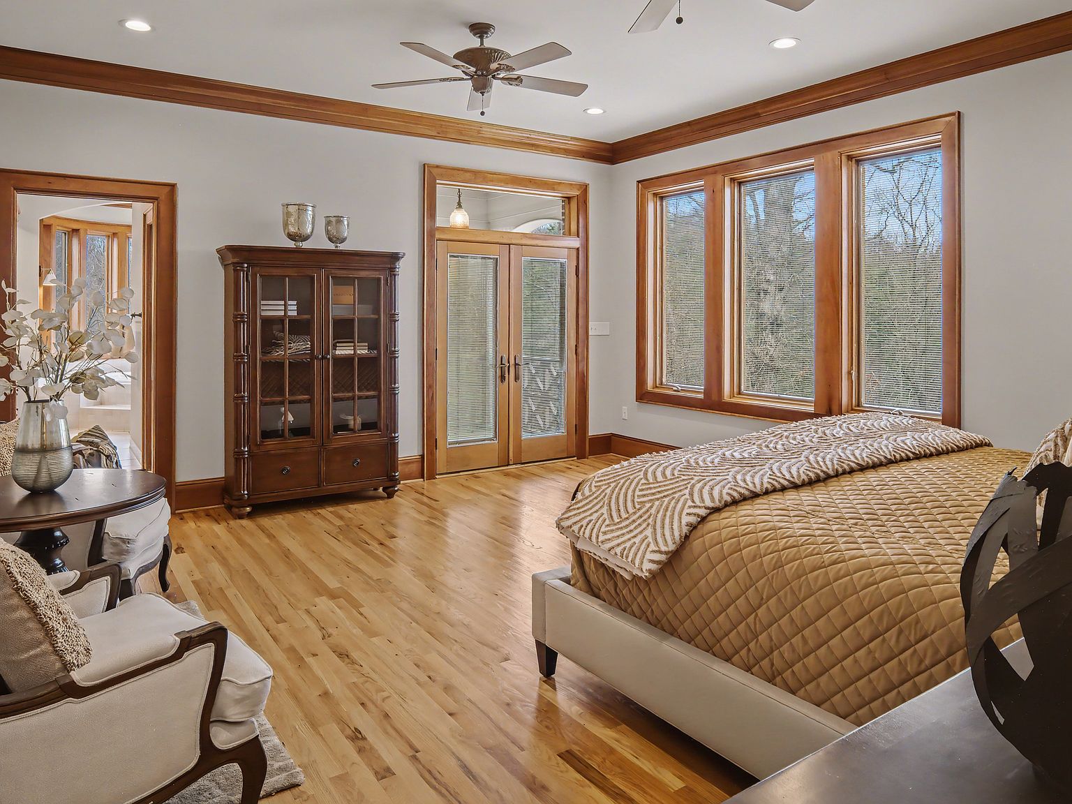 A second bedroom with a wall of windows looking onto the wooded backyard, oak floors throughout