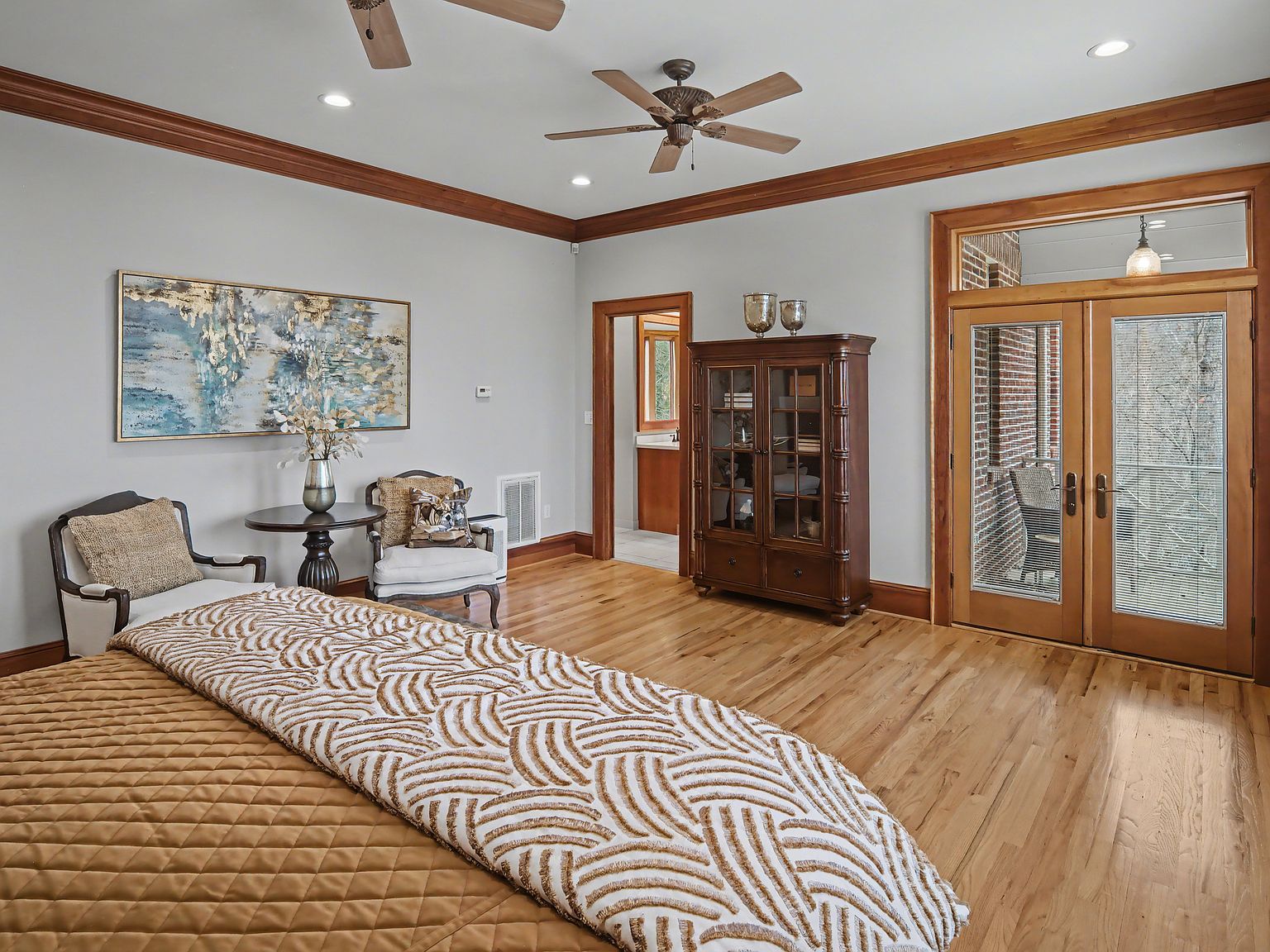 A guest bedroom with three windows on the far wall and a tall display cabinet beside the door