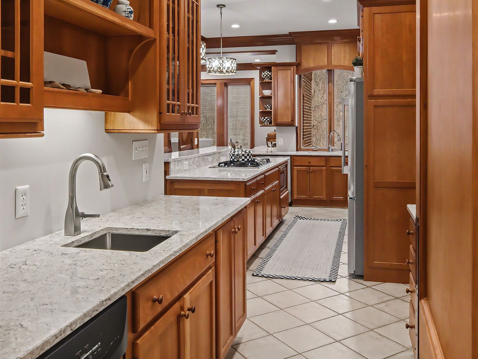 The butler's pantry with stainless under-counter appliances, custom cabinetry, and a window onto the trees